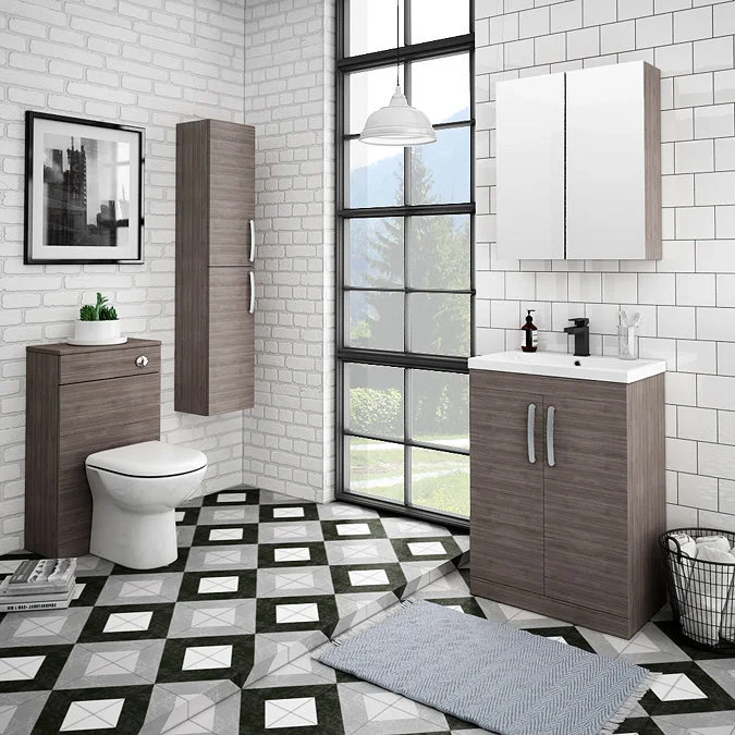 Modern bathroom with stylish grey wood-effect furniture, large window, and white subway-tiled walls. Features a compact toilet, wall-mounted storage, and a mirrored cabinet for a sleek, space-saving design.