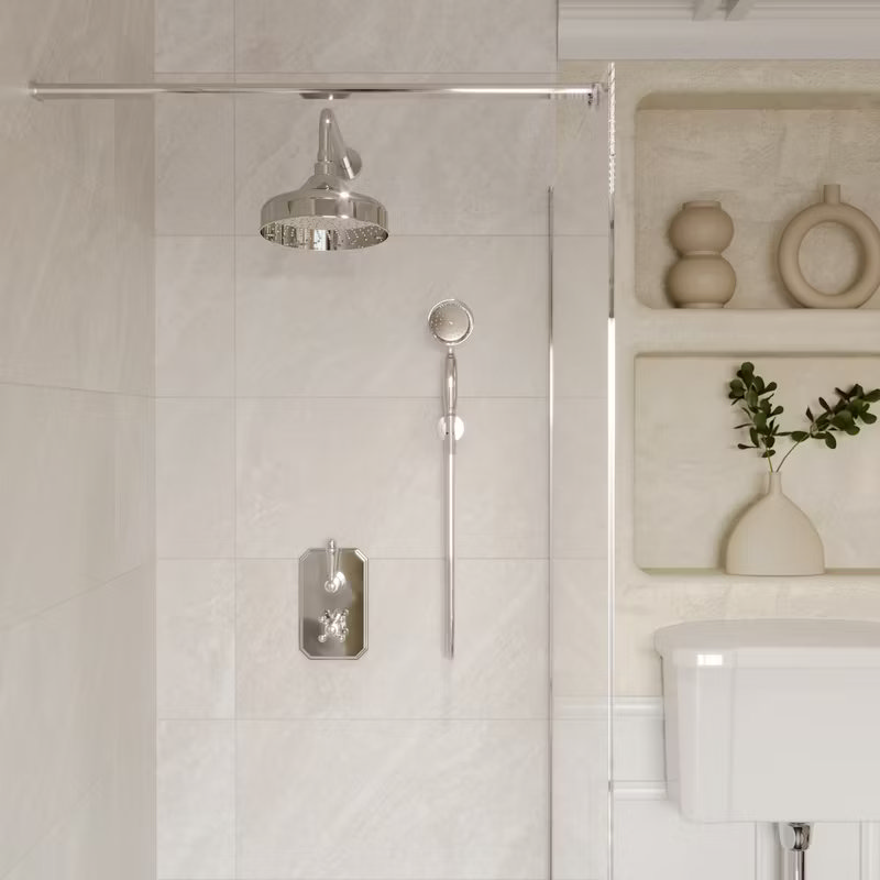 Elegant walk-in shower with chrome rainfall head and handheld attachment in a Quiet Luxury bathroom, featuring neutral tiles and minimalist recessed shelving for a calm, sophisticated feel.