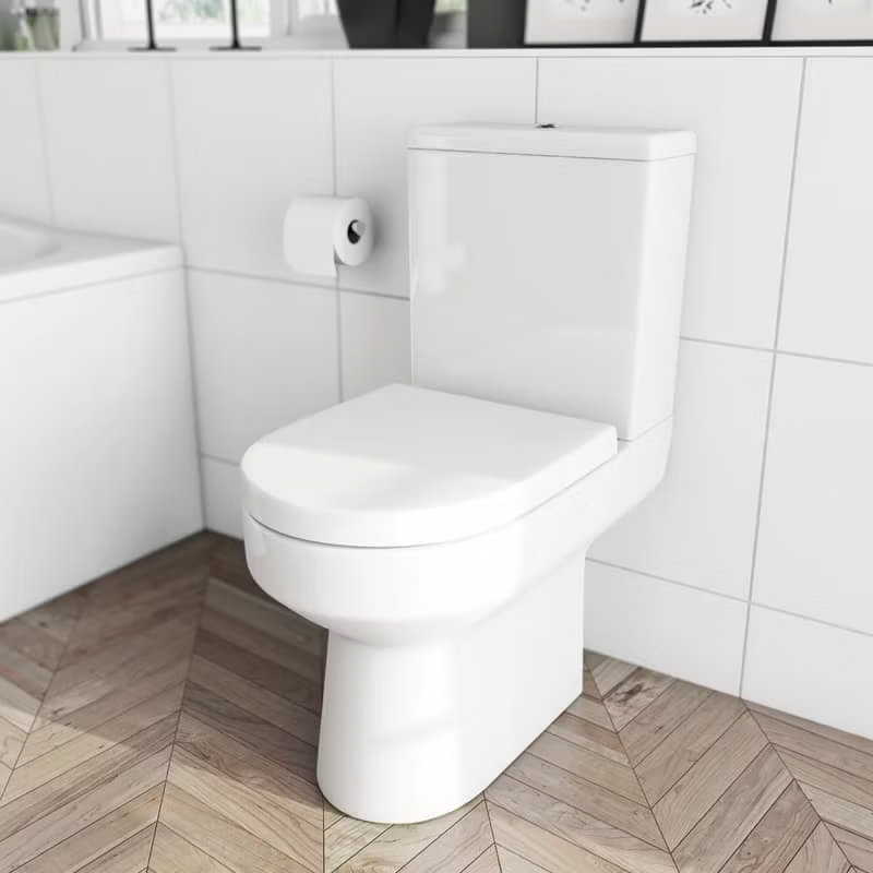 Contemporary close-coupled toilet with a minimalist design, set against white tile walls and chevron-patterned flooring in a modern bathroom.