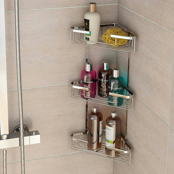 Corner shower caddy with three chrome baskets holding bottles and sponge