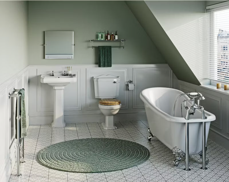 Traditional bathroom with a freestanding roll-top bathtub, pedestal sink, and classic toilet, styled with soft green accents and a vintage feel.