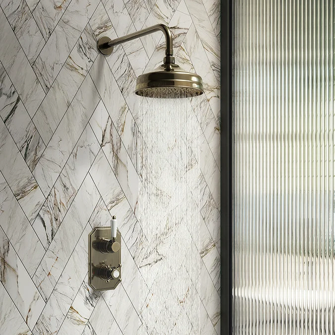 Brass rainfall showerhead with marble herringbone tiles and glass shower screen