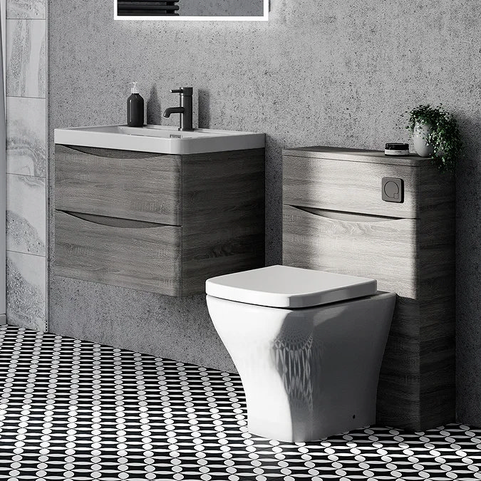 Contemporary bathroom with soft-edged floating vanity unit and toilet, featuring wood-effect finishes and a sleek design. The soft curves add a modern touch, complemented by geometric black-and-white floor tiles.