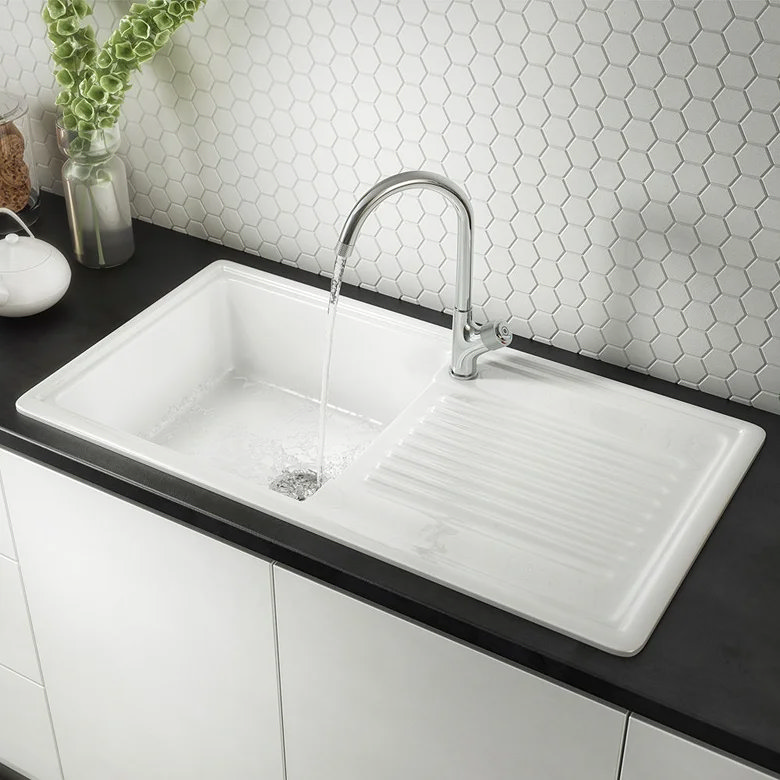 White ceramic sink and drainer, chrome tap running