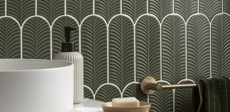 Green scalloped 3D wall tiles behind basin and brass towel rail.