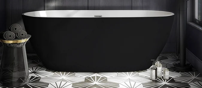 Moody dark bathroom featuring a sleek black freestanding bathtub, bold geometric floor tiles, and sophisticated wall panelling, creating a luxurious and modern retreat.