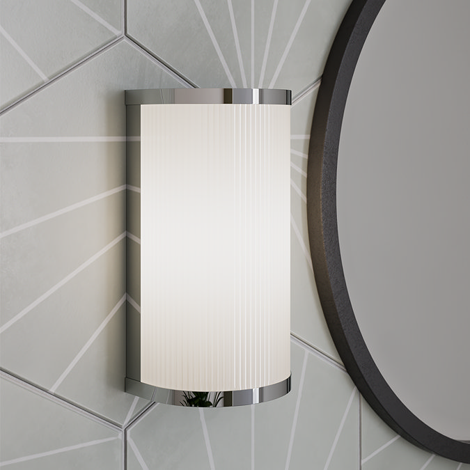 Wall-mounted chrome bathroom light next to a round mirror on geometric tiles