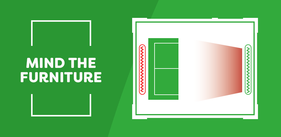 Illustration showing a living room plan with a sofa blocking one radiator (red) and a clear path to another radiator (green), with the caption “Mind the Furniture,” highlighting how furniture placement affects heat flow.