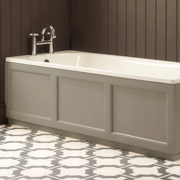 Traditional bathtub with a grey wooden panel in a bathroom featuring dark brown wall paneling and patterned floor tiles, complemented by classic chrome bath taps.