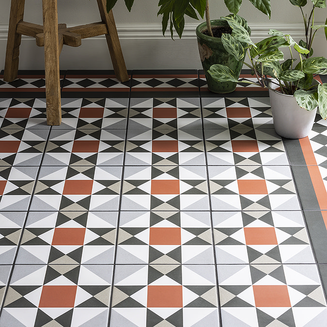 Geometric patterned floor tiles in black, white, orange, and grey with a bold border, adding a vibrant touch to the room decor.