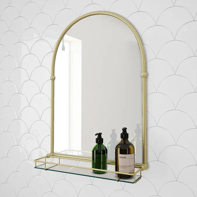 Arched gold bathroom mirror with glass shelf and white scalloped tiles