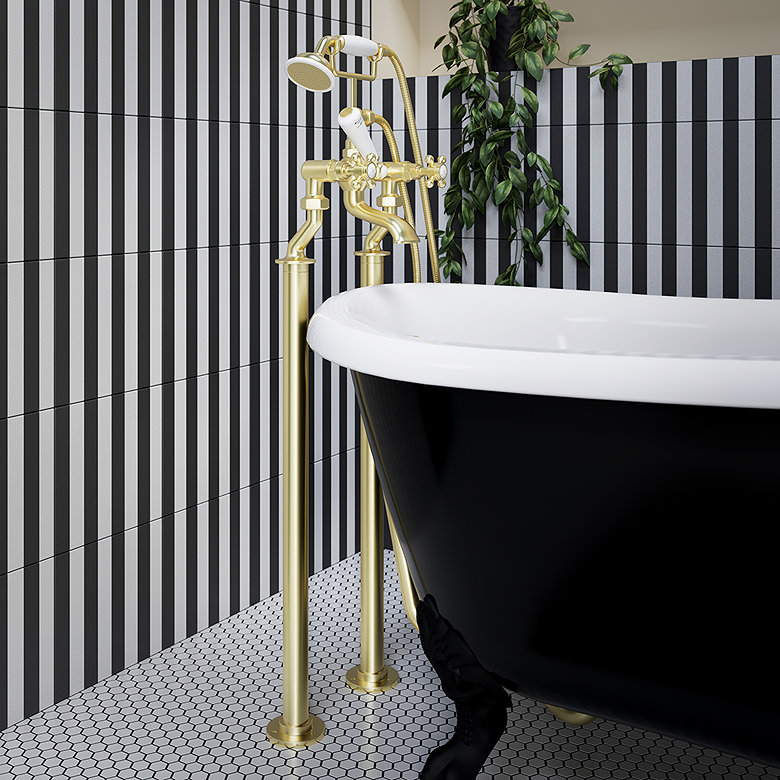 Black clawfoot bath with gold freestanding taps against black and white striped bathroom tiles.
