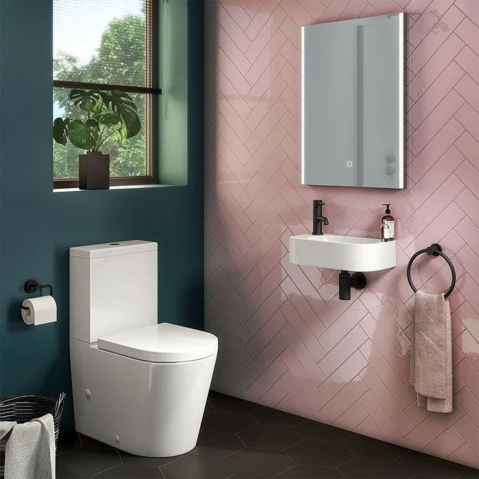 Small modern cloakroom with a white wall-hung corner basin and white toilet against pink herringbone tiles.