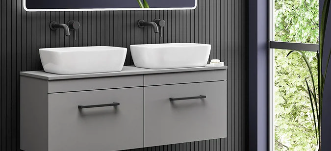 Modern his and hers bathroom with dual sinks, sleek grey floating vanity, matte black fixtures, and illuminated mirror against a dark wood panel wall. Large window showcasing natural light and greenery.