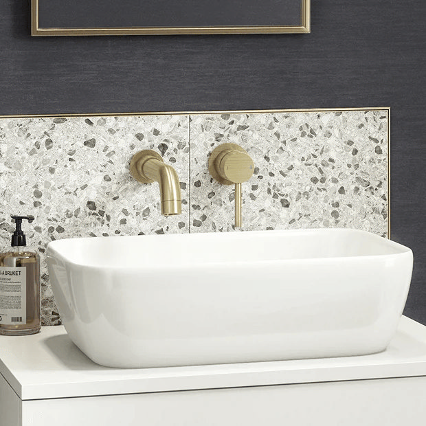 Brass wall mounted tap with terrazzo tiles on blue wall