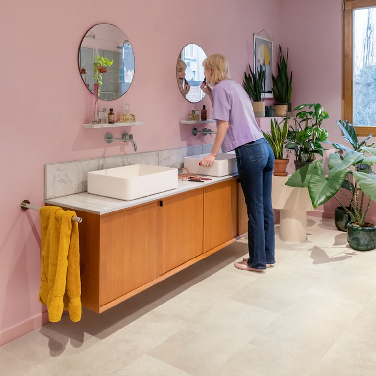 Light stone effect bathroom flooring in a pink bathroom with a wooden vanity and white countertop basins