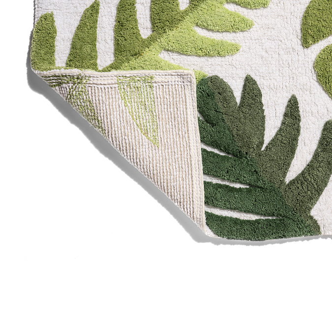 The bottom corner of the Croydex Botanical Soft Tufted Bath Mat flipped up showing the anti-slip feature on the underside, pictured on a white background.