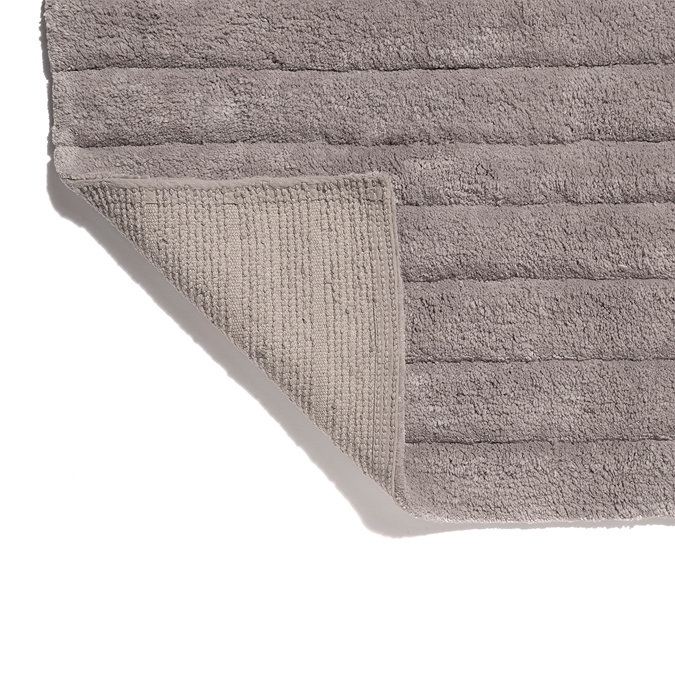 The bottom corner of the Croydex Grey Arched Bath Mat flipped up showing the anti-slip feature on the underside.