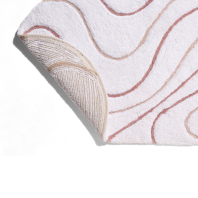 Corner of the Croydex Pink and White Swirls Bath Mat flipped up to show the anti-slip feature on the underside.