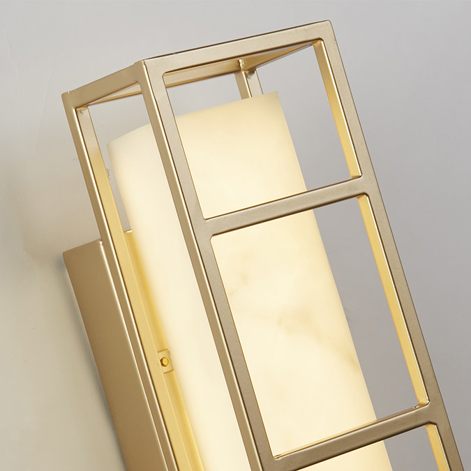 Close‑up of the matt gold open frame and softly glowing marble‑effect resin diffuser of the rectangular wall light.