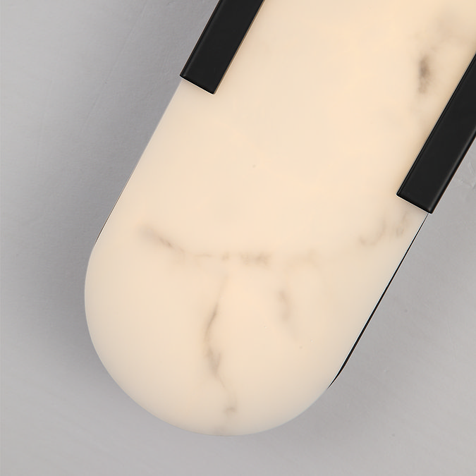 Close‑up view of the wall light’s white marble‑effect diffuser with soft veining, bordered by matte black trim.