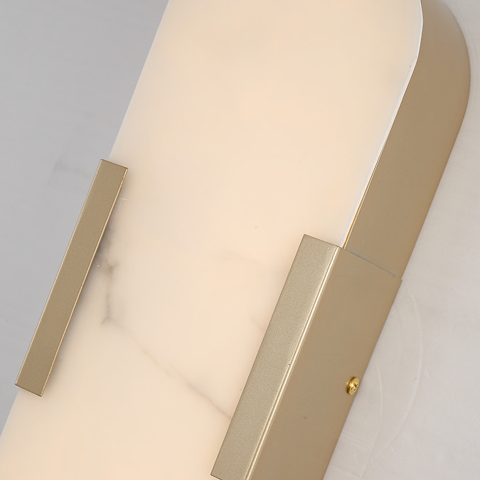 Close‑up view of the wall light’s white marble‑effect diffuser with soft veining, bordered by matte gold trim.