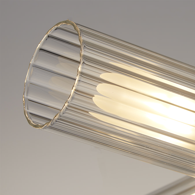 Close‑up of one ribbed clear glass shade from the four‑light ceiling fixture, showing warm illumination inside the textured cylinder.