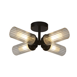 A matt black four‑light flush ceiling fitting with four ribbed glass cylinders arranged in a cross shape, each glowing warmly.