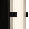 Close‑up of the matt black clamp wall light showing the glowing ribbed opal glass tube and the black metal clamp securing it at the centre.