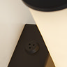 Close‑up of the matt black wall light showing the base of the marble‑effect cylinder and a small circular mounting detail on the backplate.
