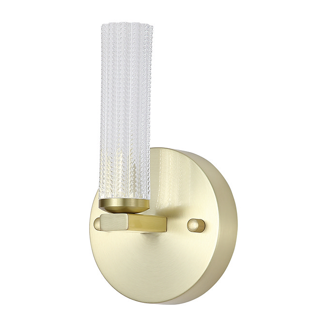 A modern wall‑mounted light with a round satin‑brass base and a short vertical cylinder of textured clear acrylic, shown with the light switched off.
