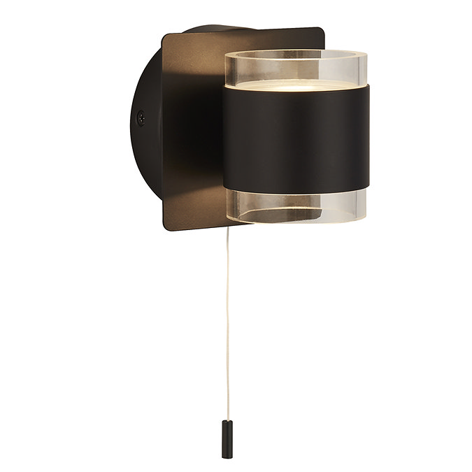 A matt black up‑and‑down wall light with a glowing clear acrylic cylinder that emits light upward and downward, with a pull‑cord hanging below.