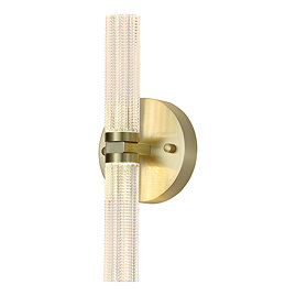 This image shows a modern wall‑mounted light fixture. It has a cylindrical light bar running vertically, with textured clear acrylic that diffuses the light. The cylinder is attached at the centre to a round satin‑brass metal base, giving it a sleek and elegant appearance. The fixture casts light both upward and downward and has a warm, contemporary look.