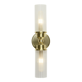 A satin brass up‑and‑down wall light with two clear ribbed glass shades, each glowing softly to show the light is switched on.