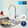 Grohe StartLoop kitchen mixer tap shown in use over a sink, highlighting the high C-spout and swivel function.