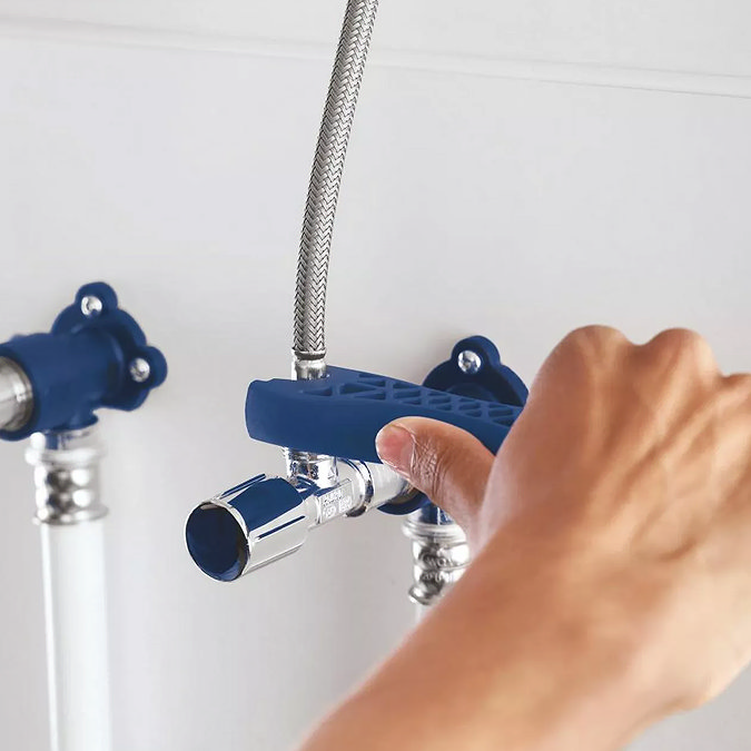 Under-sink view showing Grohe Swift kitchen tap flexible hoses being connected to isolation valves.