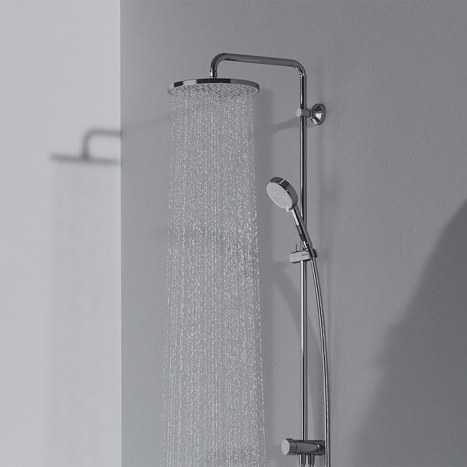 The Ideal Standard Ceratwist T25 Exposed Shower Kit with Fixed Head & Handset - 12 l/min pictured at a side angle in a grey room. The overhead shower head is on, showing how it looks when the water is running.