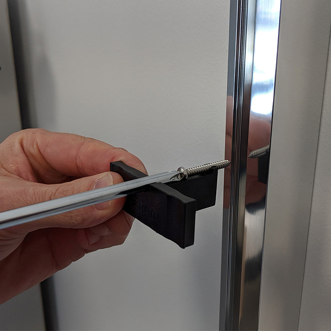 Installer fitting the Merlyn IQ shower wall profile using the easy-fit system, demonstrating secure fixing.
