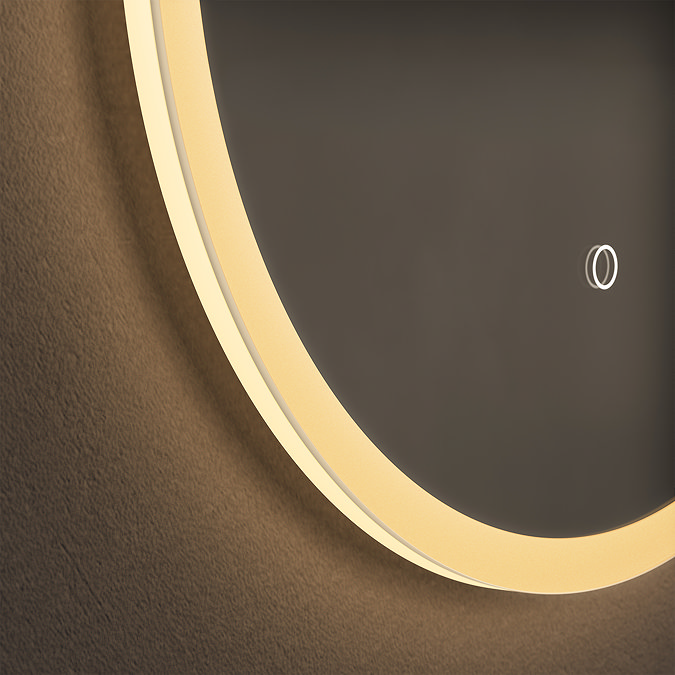 Close up of the bottom corner of the Roxbury Illuminated Capsule Mirror, showing the light strip's warm-toned glow.