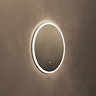 The Roxbury Illuminated Round Mirror pictured on a plain beige wall, showing the mirror omitting a bright, cool glow.
