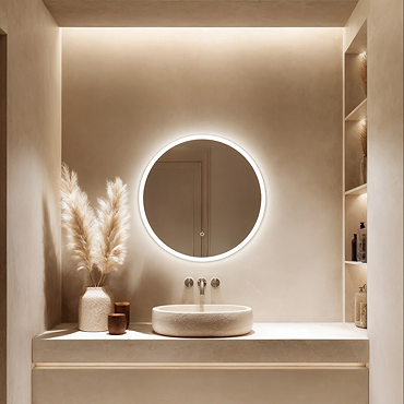 The Roxbury Illuminated Round Mirror pictured on a plain beige wall, showing the mirror omitting a bright, cool glow.