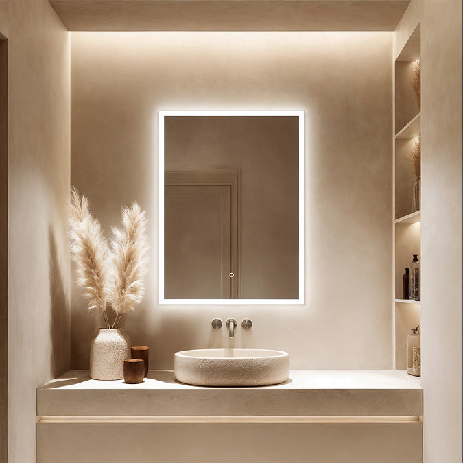 The Roxbury 600 x 800mm Illuminated Rectangular Mirror with Demister Pad pictured lit up in a modern beige toned bathroom, fixed above a basin.
