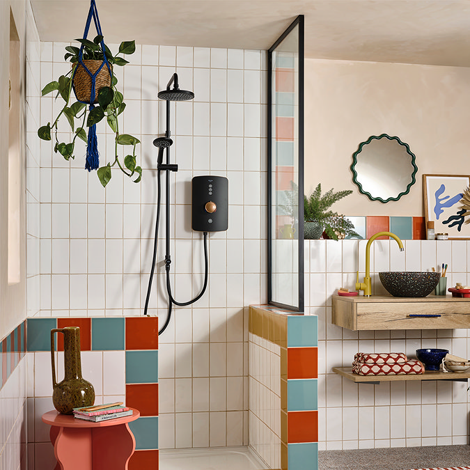 Triton Amala DuElec electric shower installed in a bathroom setting, showing the brushed copper and black shower unit with dual outlet rainfall and handheld shower heads.